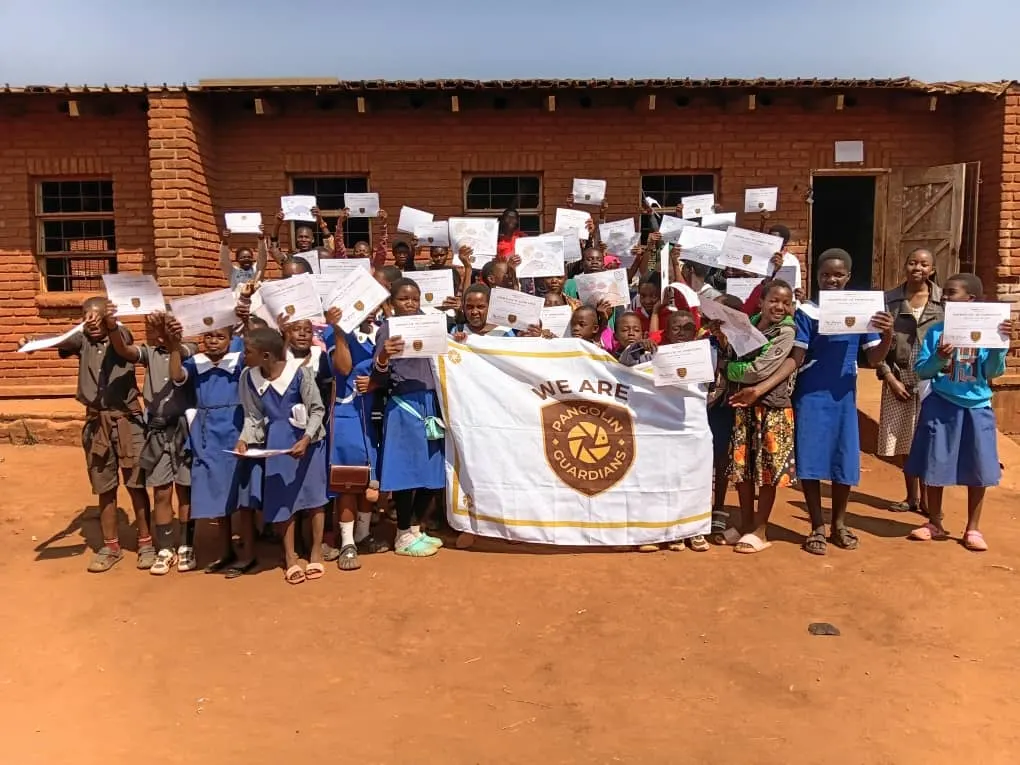 Learners holding their Pangolin Guardian certificates behind a “We are Pangolin Guardians” banner